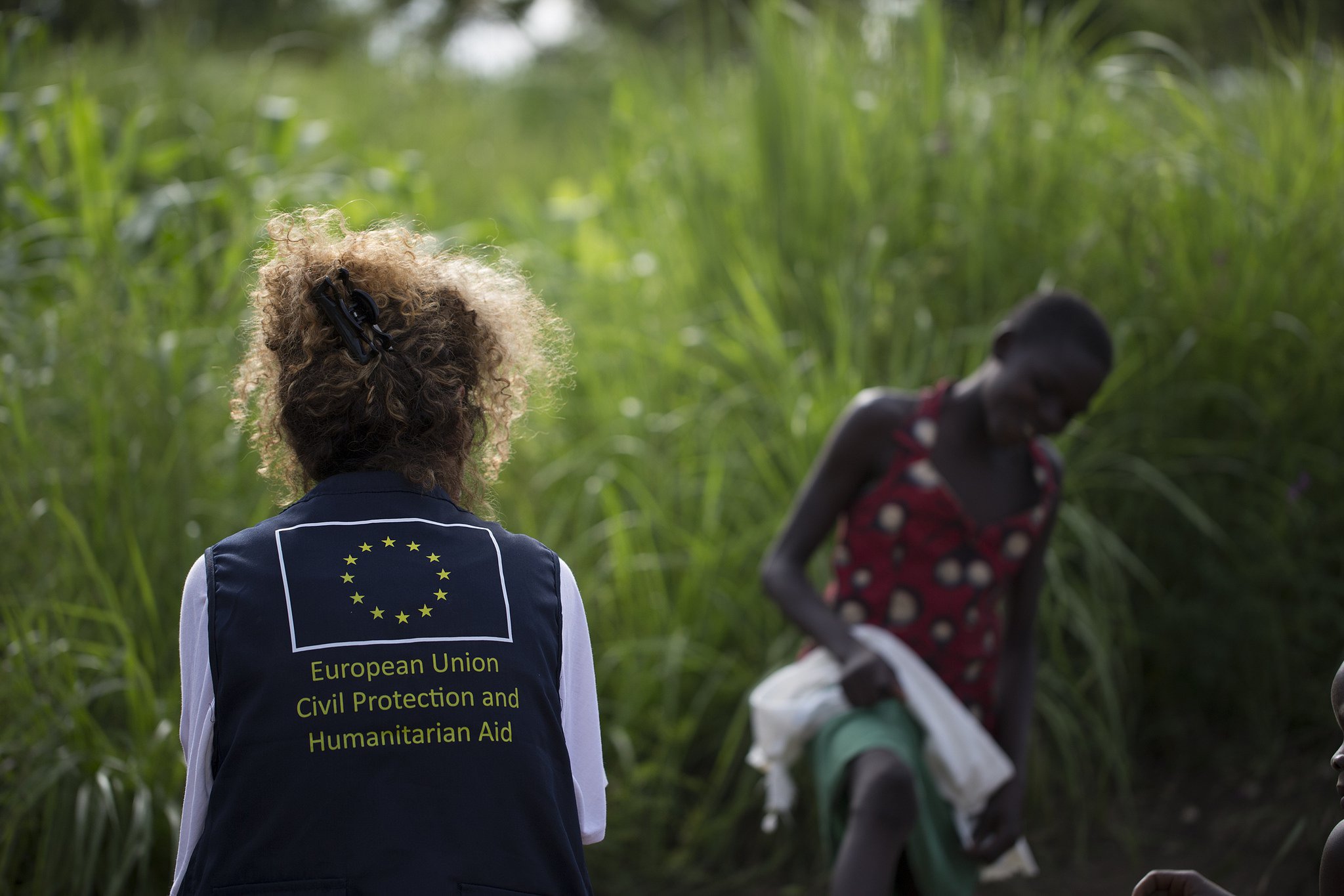A European Union Civil Protection and Humanitarian Aid staff member chats with a young girl  at Imvepi refugee settlement, Uganda. Photo © EU/ECHO/Edward Echwalu