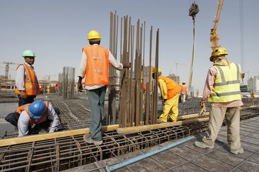 An engineer supervises the work of foreign workers at a construction site in Doha.