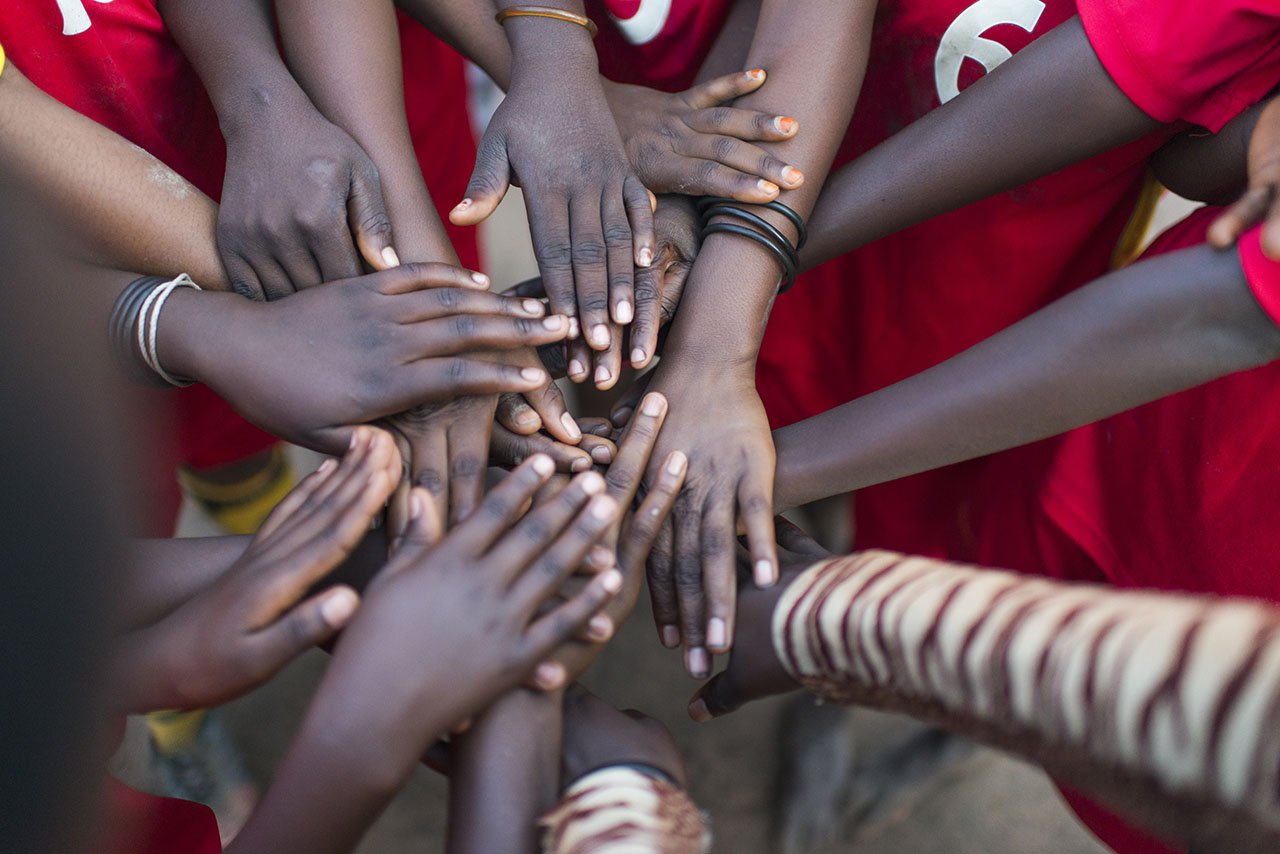 A refugee football team touches hands before a game at Lusenda refugee camp