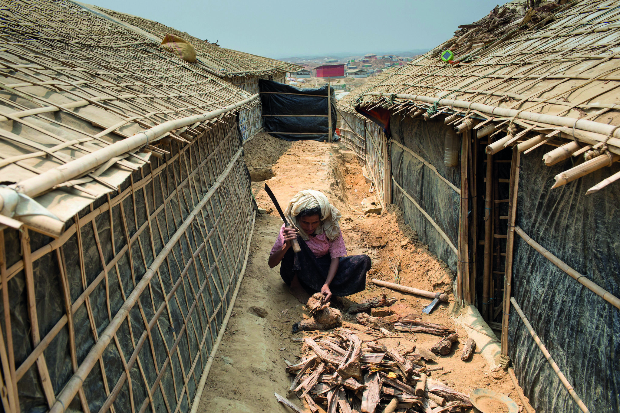 A Rohingya refugee chops firewood for cooking in Kutupalong megacamp